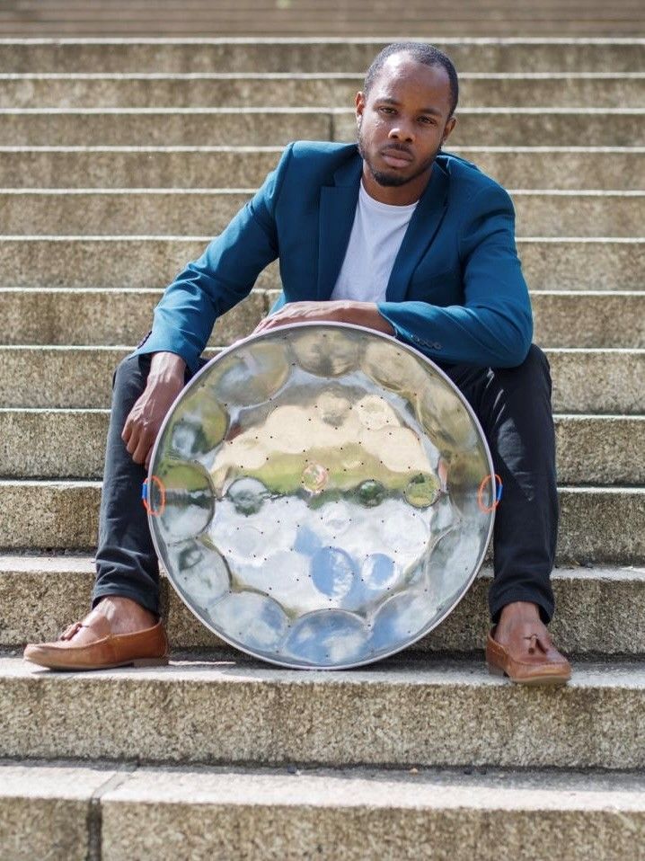 Marlon Hibbert leaning on a steel drum, sat at the bottom of a staircase